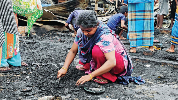 Burnt furniture and charred clothes -- all that remain of their hopes and dreams, shattered by yesterday’s blaze at the slum near port city’s Amin colony. This photo of a woman trying to salvage her belongings was taken yesterday. Photo: Star
